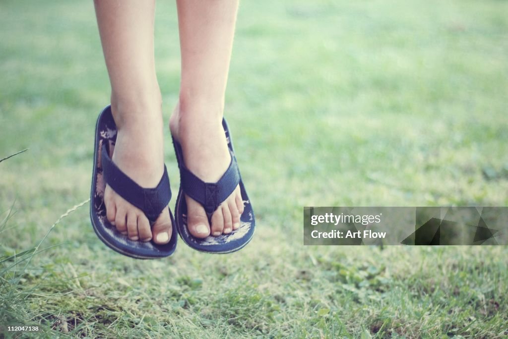 Child's dangling feet in flip flops