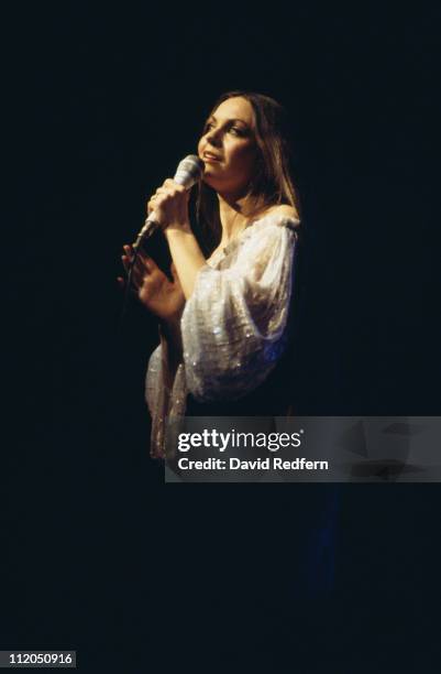 Crystal Gayle, U.S. Country music singer, singing into a microphone during a concert, circa 1975.