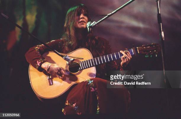 Melanie, U.S. Singer-songwriter, performing live in concert, playing the guitar while singing into a microphone, circa 1970.
