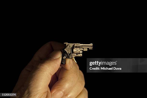 miniature gun in hand on black background - feuerwaffen abzug stock-fotos und bilder