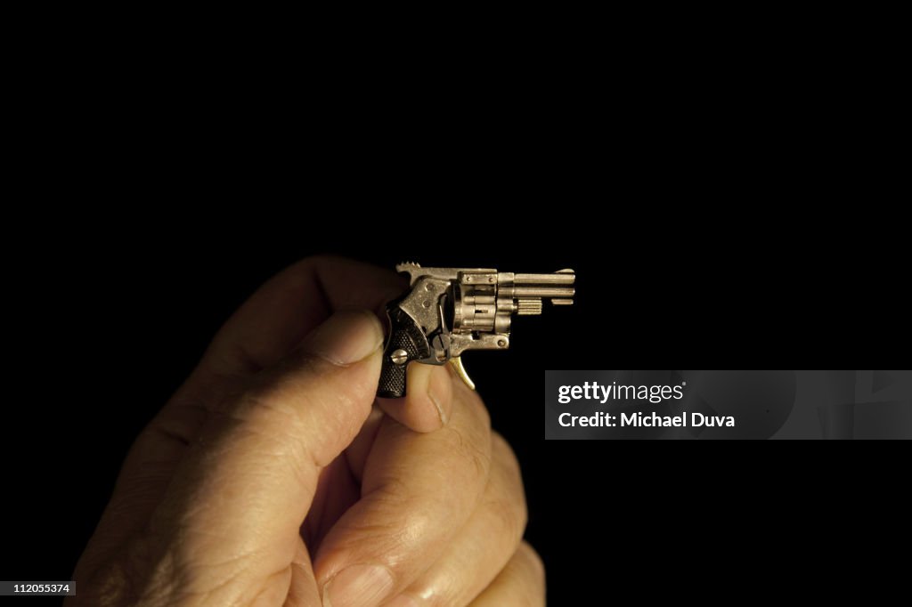 Miniature gun in hand on black background