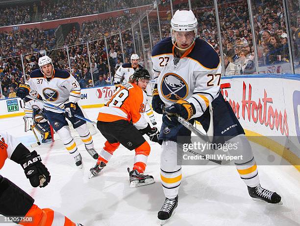 Shaone Morrisonn and Matt Ellis of the Buffalo Sabres battle for the puck against Claude Giroux of the Philadelphia Flyers at HSBC Arena on March 8,...