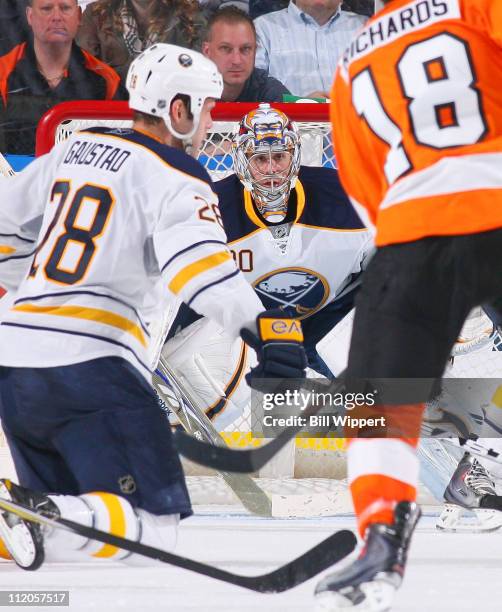 Ryan Miller of the Buffalo Sabres focuses on the puck between teammate Paul Gaustad and Mike Richards of the Philadelphia Flyers at HSBC Arena on...