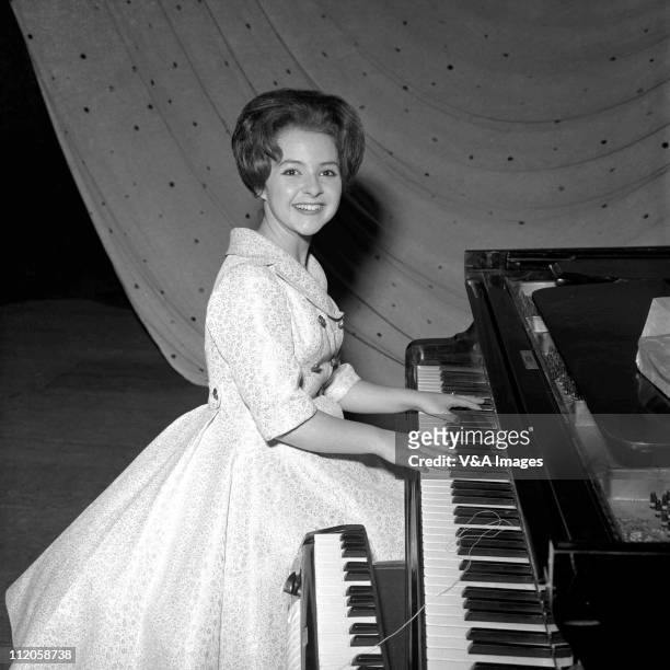 Brenda Lee, posed, backstage, playing piano, 1960.