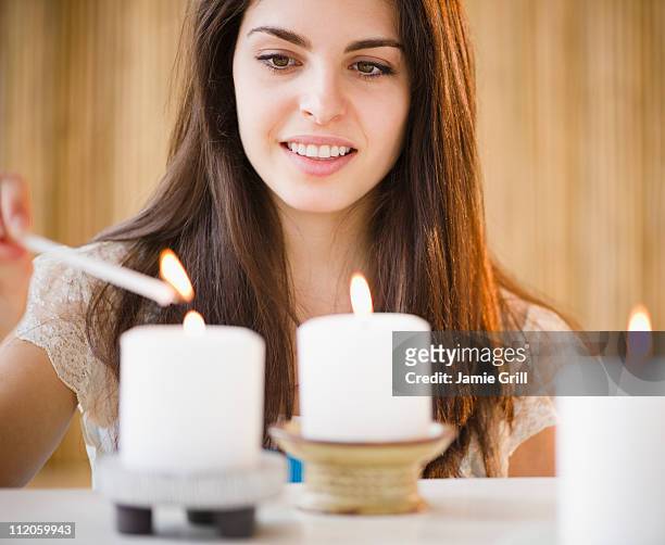 young woman lighting candles - candela attrezzatura per illuminazione foto e immagini stock