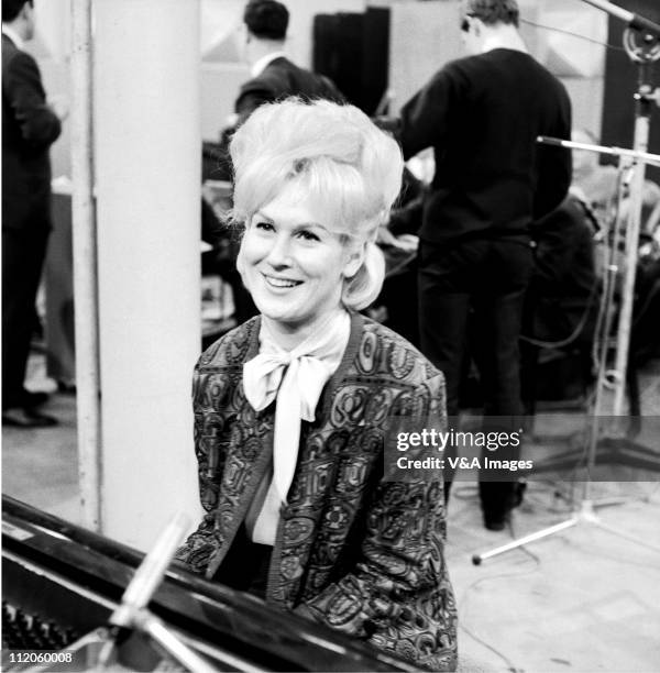 Dusty Springfield, posed, in recording studio sitting at piano, 1962.