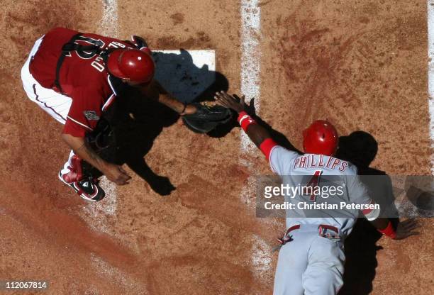 Brandon Phillips of the Cincinnati Reds is tagged out at home plate by catcher Henry Blanco of the Arizona Diamondbacks as he attempts to score...