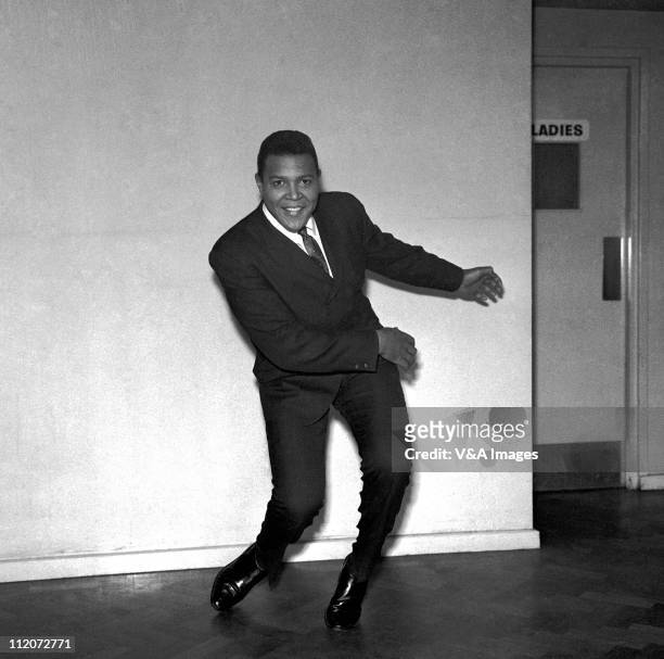 Chubby Checker, posed, in corridor, doing the twist, 1961.