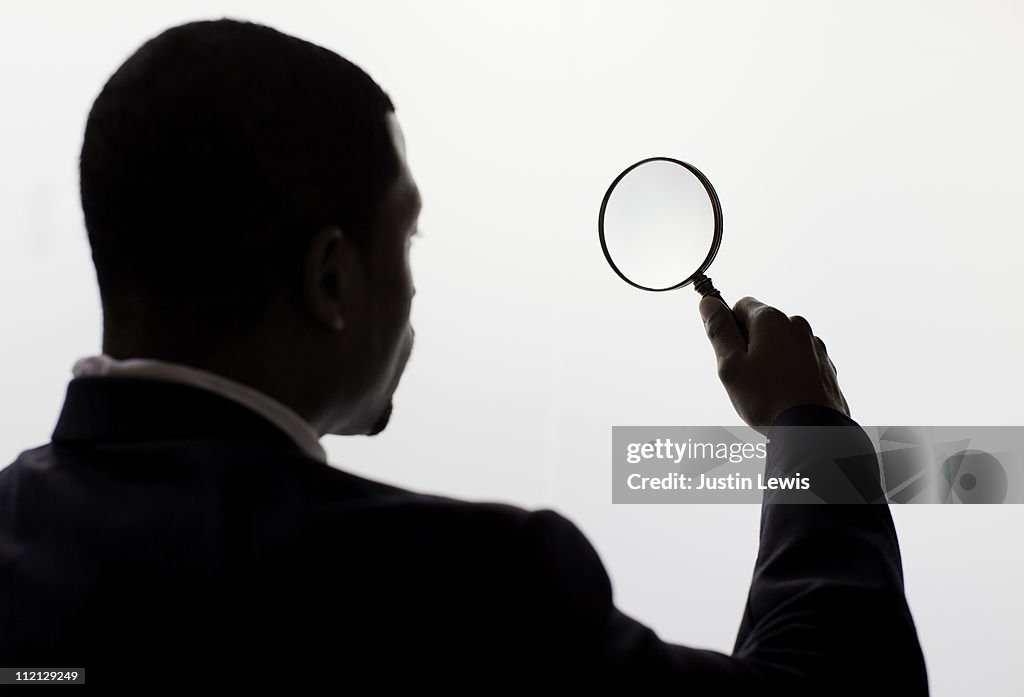 A man looking through a magnifiing glass.