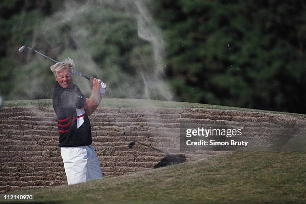Greg Norman of Australia looks on as sand splashes back at him as he hits out of a bunker during the third round of the 119th British Open...