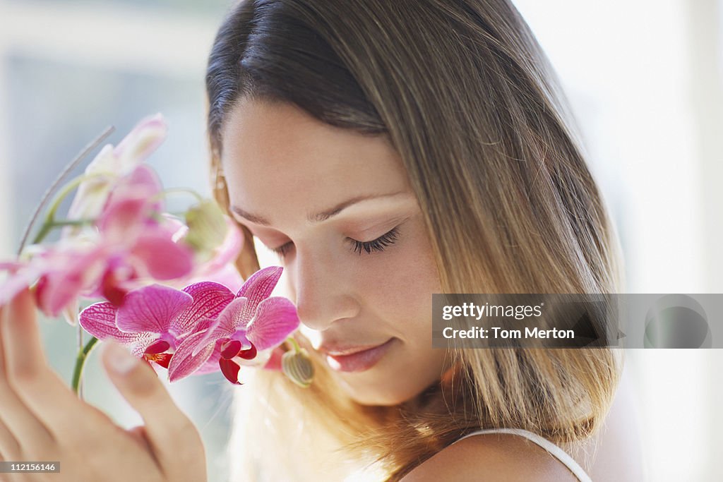 Woman with eyes closed smelling orchid