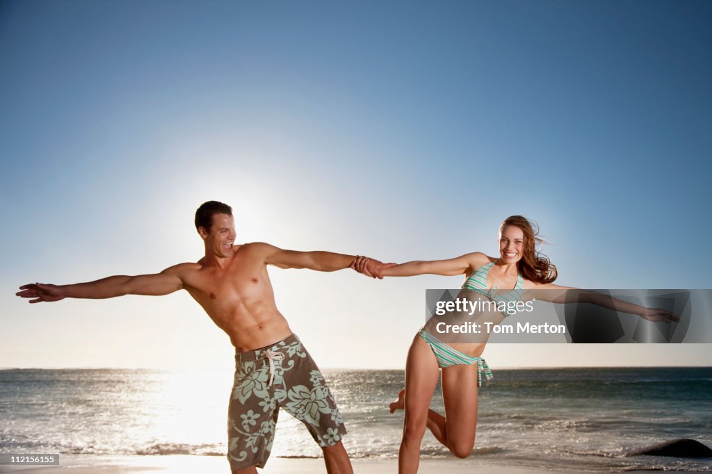 Playful couple holding hands at beach