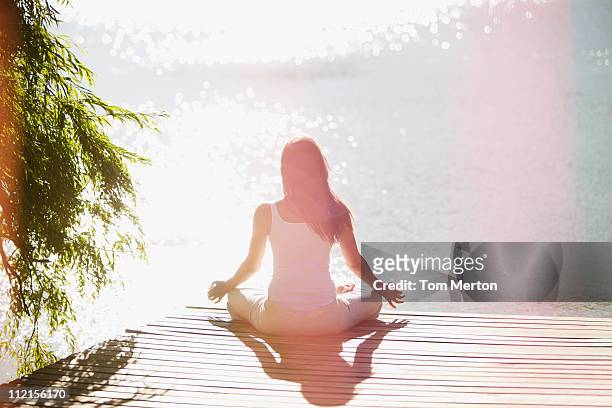 frau üben yoga auf dem pier - spirituality stock-fotos und bilder