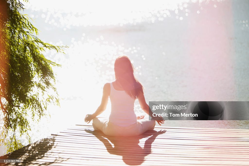 Woman practicing yoga on pier