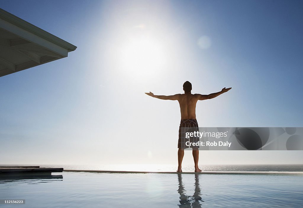 Man standing near swimming pool with arms outstretched