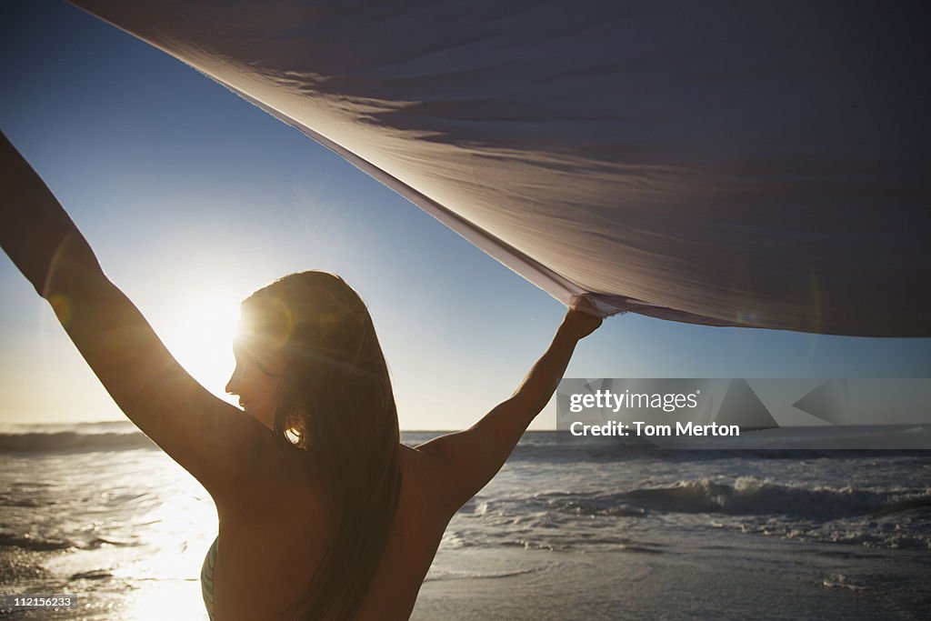 Femme avec bras tenant tissu sur la plage