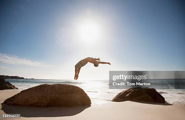 uomo sulla spiaggia mentre esegue un backflip - fare le capriole all'indietro foto e immagini stock