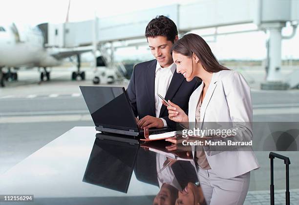 business people using laptop together at airport - mid adult men stock pictures, royalty-free photos & images
