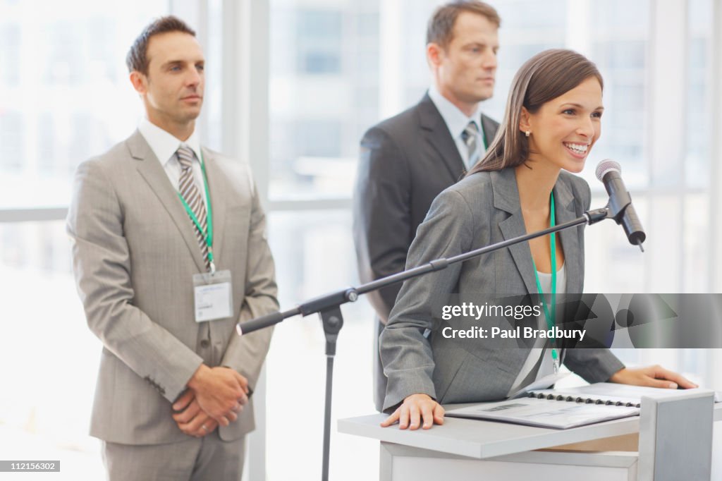 Business woman speaking in to microphone in office