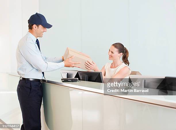 delivery man handing box to receptionist - pre reception stockfoto's en -beelden