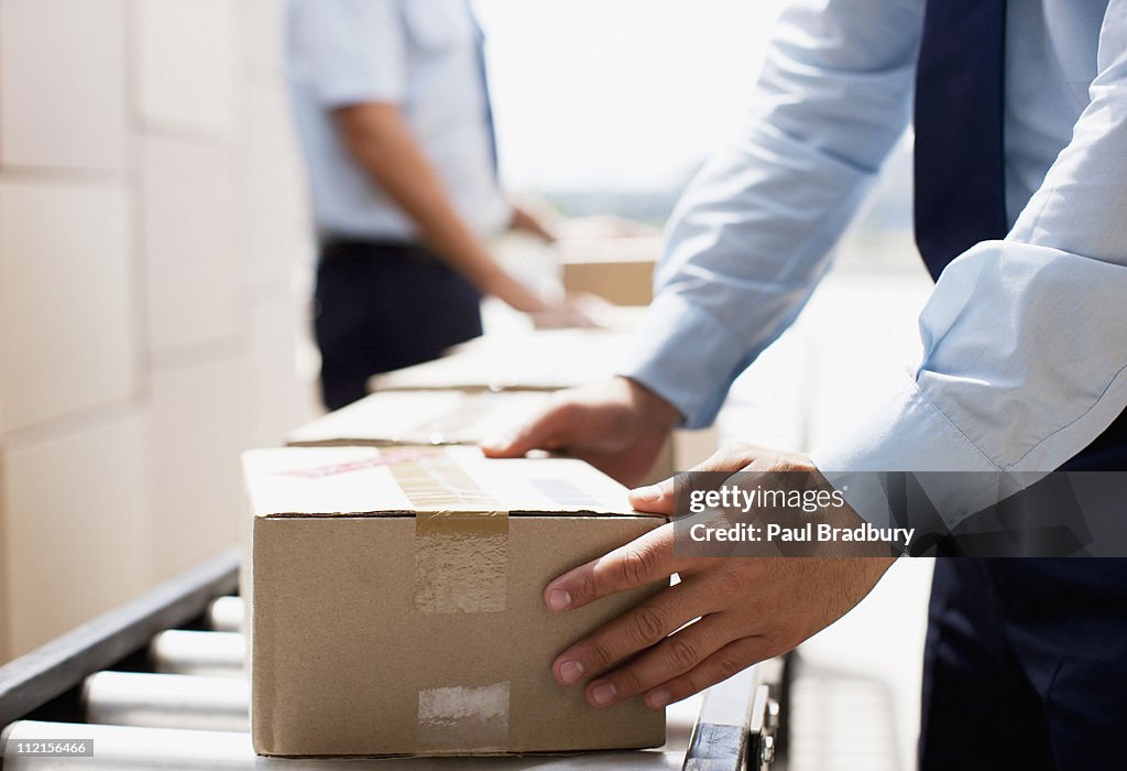 Worker taking box from conveyor belt in shipping area