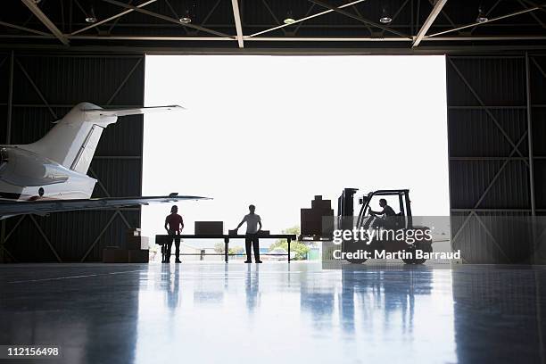 lavoratori, scatole e carrello elevatore a forca in hangar - hanger foto e immagini stock