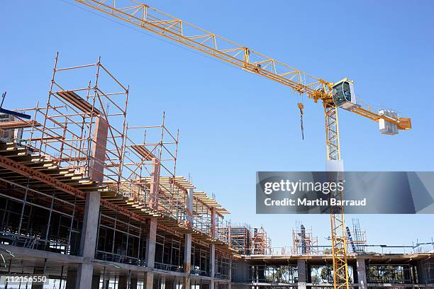 kran auf baustelle - baustelle gerüst sonne stock-fotos und bilder