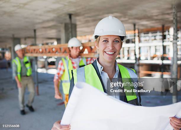 construction worker holding blueprints on construction site - business protection stock pictures, royalty-free photos & images