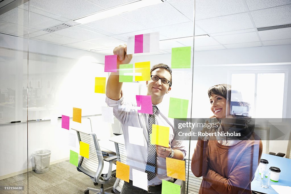 Business people looking at adhesive notes in conference room
