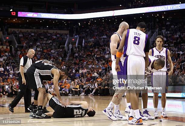 Manu Ginobili of the San Antonio Spurs lays on the court in pain as teammates Tim Duncan and Antonio McDyess lean in following a collision with Grant...