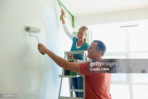 couple painting wall together - couple painting stock pictures, royalty-free photos & images