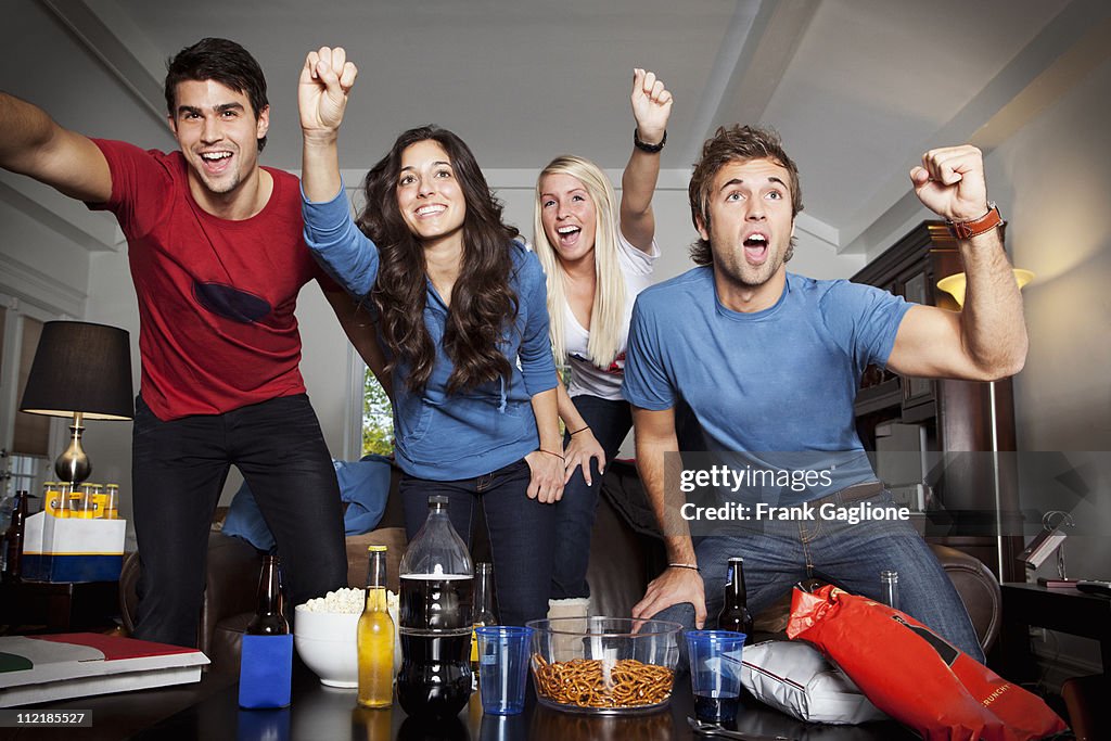 Four Friends Cheering in Front of TV.