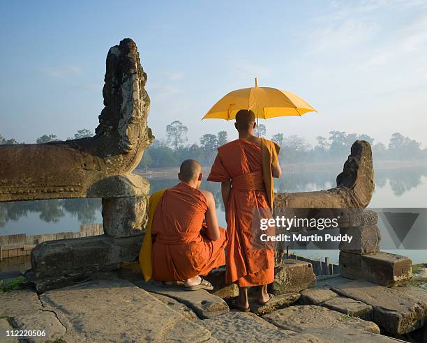 buddhist monks standing next to stone carvings - angkor stock pictures, royalty-free photos & images