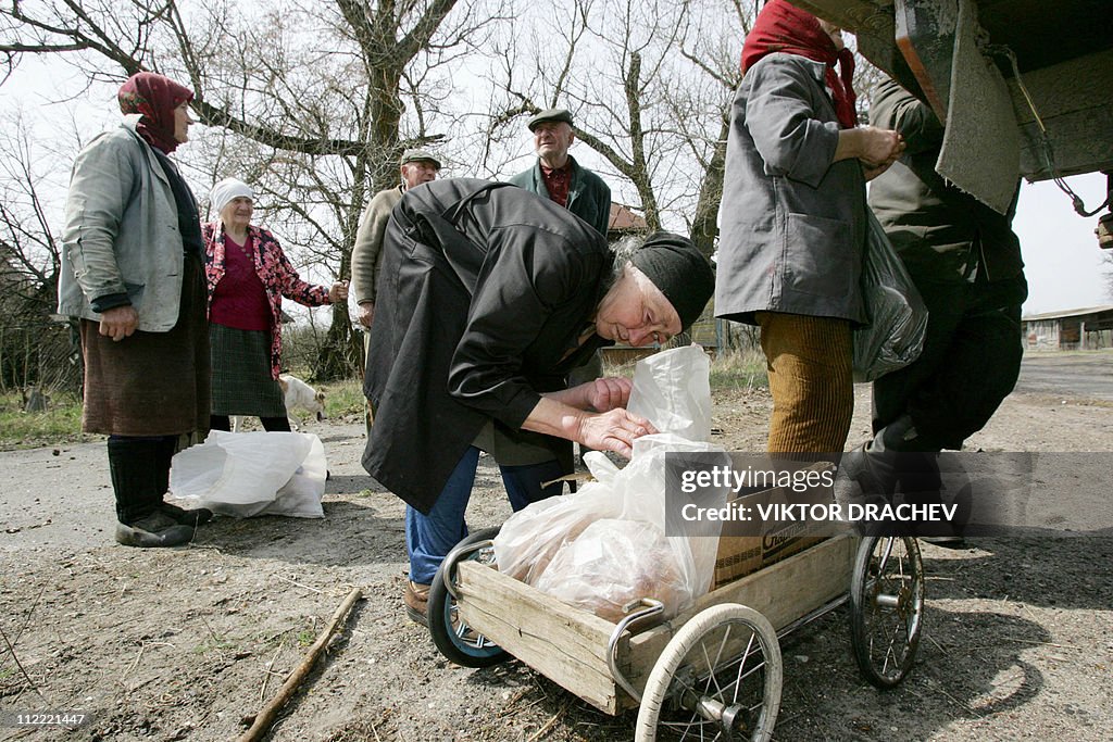 An old woman looks in her bag as others