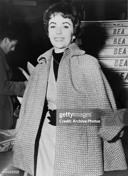 Actress Elizabeth Taylor, with short cropped hair and wearing a cape, arrives at an airport on a BEA plane, 1950s.