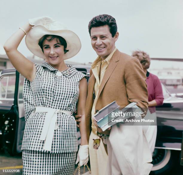 Elizabeth Taylor and Eddie Fisher, circa 1960. Taylor wears a black and white checked outfit with white wide brimmed hat and gloves.