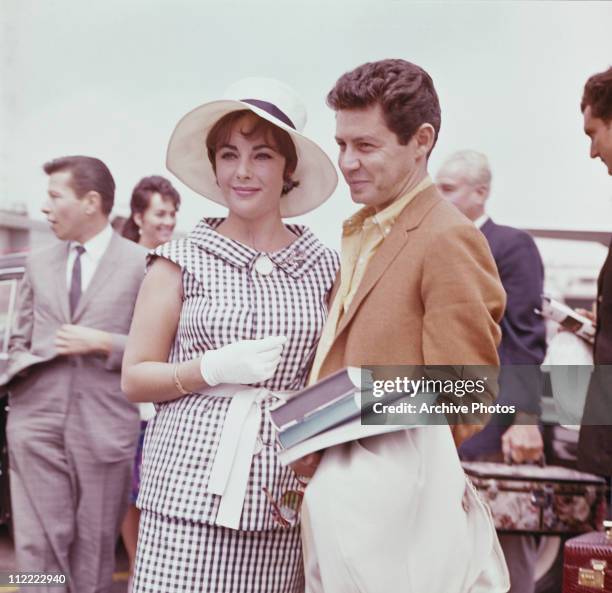 Elizabeth Taylor and Eddie Fisher, circa 1960. Taylor wears a black and white checked outfit with white wide brimmed hat and gloves.