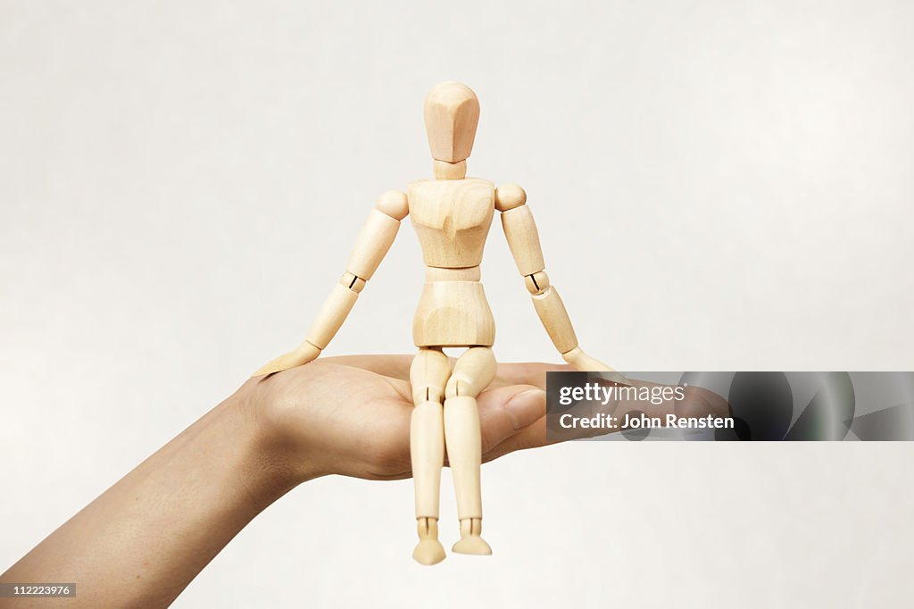 Hand holding small wooden carved figure