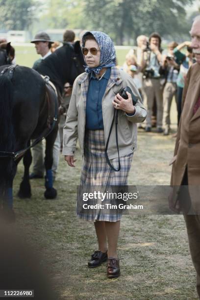 Queen Elizabeth II, wearing a headscarf and a tartan skirt, at the Royal Windsor Horse Show, held at Home Park in Windsor, Berkshire, England, Great...