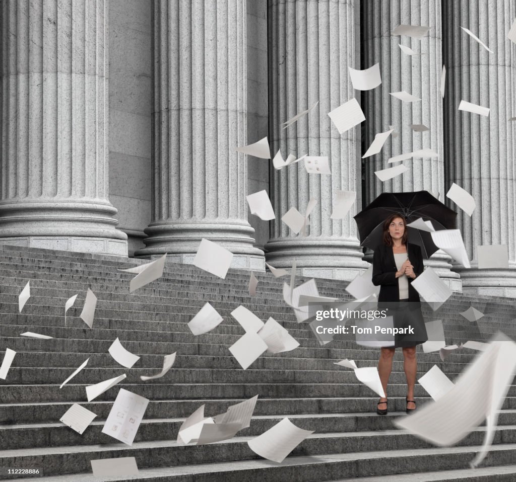 Mixed race businesswoman on steps with swirling papers
