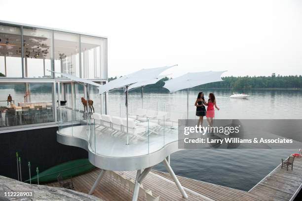 women on balcony of modern lake house - capital architectural feature - fotografias e filmes do acervo