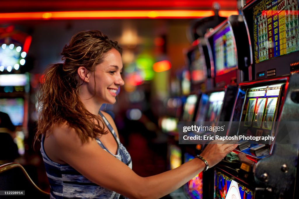 Caucasian woman playing slot machine in casino