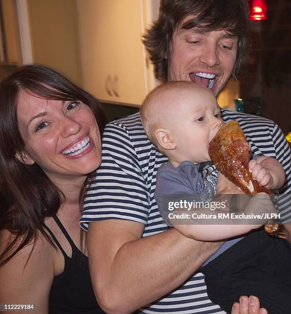 parents with baby boy eating turkey leg - turkey leg stock pictures, royalty-free photos & images