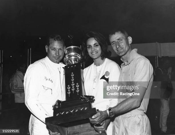 Race winners Lloyd Ruby and Ken Miles are joined in victory lane by the reigning Miss Universe, Corinna Tsopei of Greece, following their win in the...