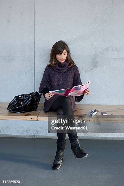 germany, leipzig, woman sitting and reading magazine - mujer revista fotografías e imágenes de stock