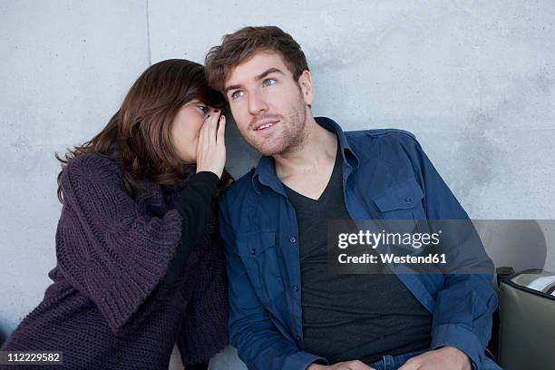 germany, leipzig, university students sitting and whispering - woman whisper to man stockfoto's en -beelden