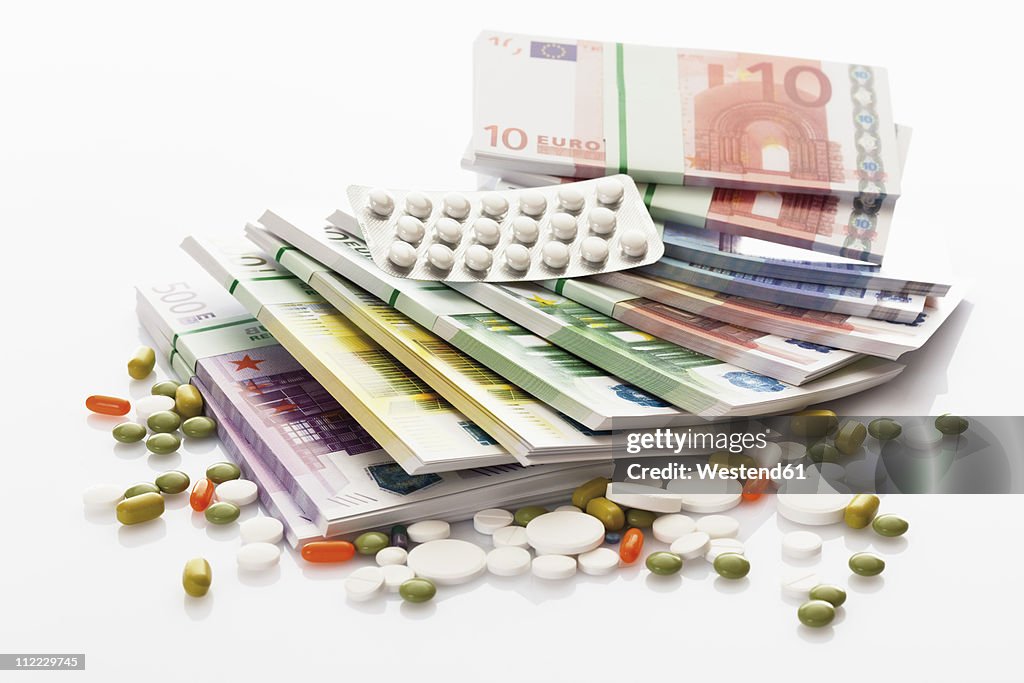 Mixed tablets with bundles of euro notes on white background