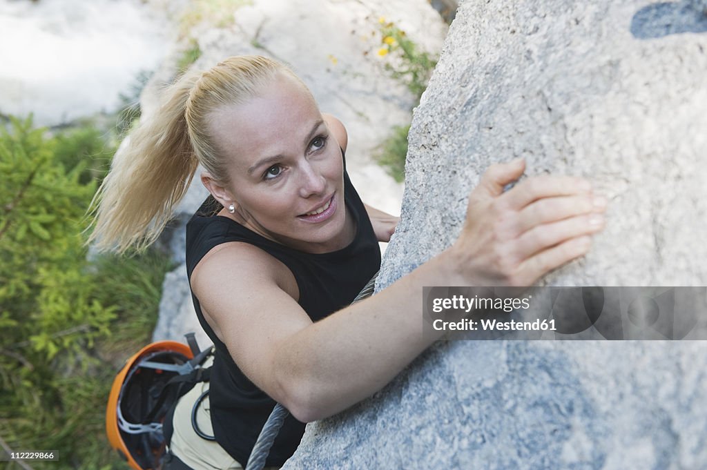 Austria, Steiermark, Ramsau, Silberkarklamm, Woman climbing on rock, elevated view