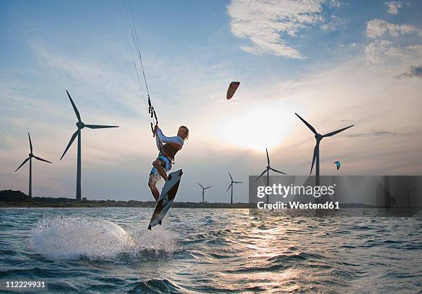 croatia, zadar, kitesurfer jumping in front of wind turbine - offshore windfarm stock-fotos und bilder