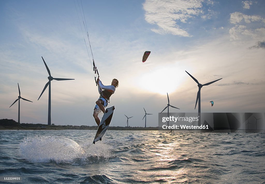 Croatia, Zadar, Kitesurfer jumping in front of wind turbine